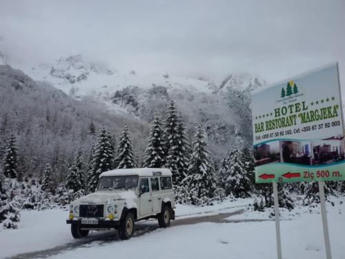 a truck driving down a snow covered road with a sign at Hotel Margjeka in Valbonë
