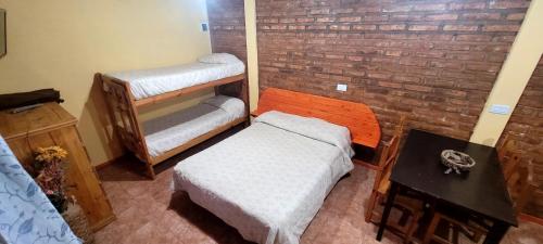 a room with two beds and a brick wall at Cabañas Clarita in Dina Huapi