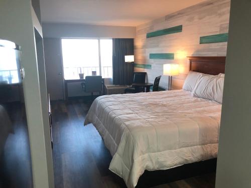 a hotel room with a large bed and a desk at Gazebo Inn Oceanfront in Myrtle Beach