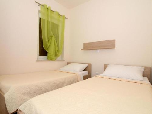 2 Betten in einem Zimmer mit grünem Vorhang in der Unterkunft Apartmani Barbara in Ljubač