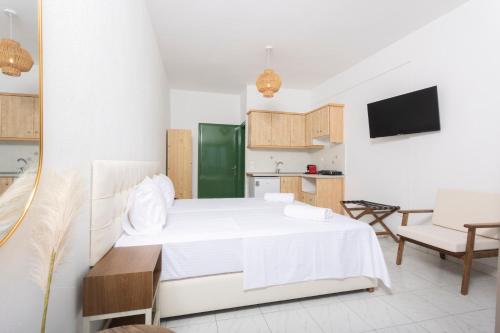 a bedroom with a white bed and a kitchen at D&G Apartments in Agia Paraskevi