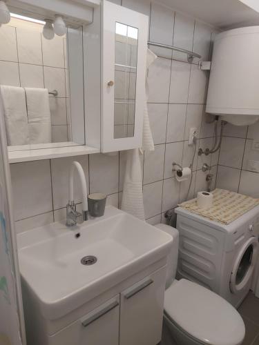 a white bathroom with a toilet and a sink at Mala placa in Senj