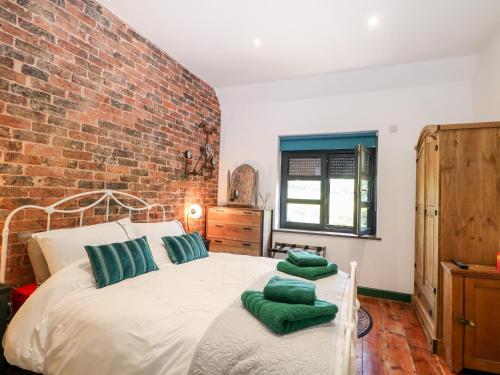 a bedroom with a brick wall and a bed with green pillows at The Masters House in Hassocks