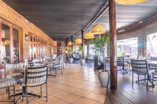 un comedor con mesas, sillas y ventanas en Zebula Golf Estate & Spa Executive Holiday Homes en Mabula