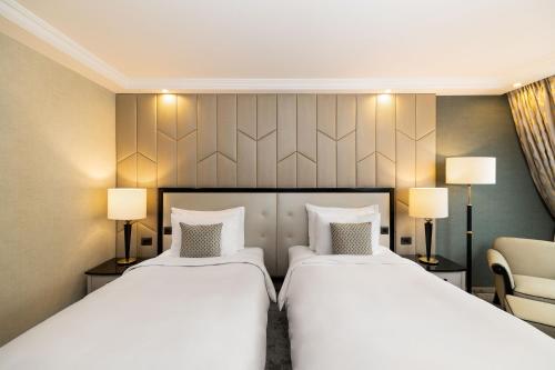 a hotel room with two beds and a chair at Kempinski Hotel Corvinus Budapest in Budapest