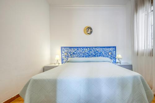 a bedroom with a bed with a blue and white bedspread at Jardins I 22 Roses - Immo Barneda in Roses