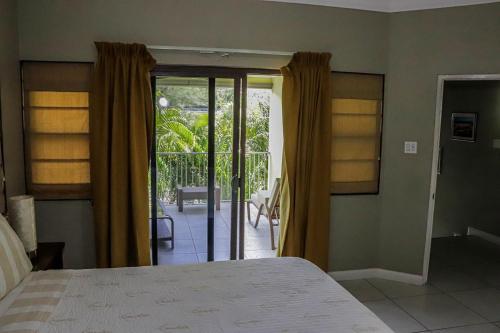 a bedroom with a bed and sliding doors to a patio at Water Mills- Beach Apartments in Mammee Bay