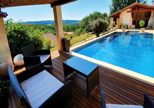 a swimming pool on a wooden deck with chairs next to it at Villa 'Deux Couples' dans le Paradis des Gourmands, de paix et de quiétude - inclus Soirée Dégustation Vin & Viande in Saint-Jean-de-Côle
