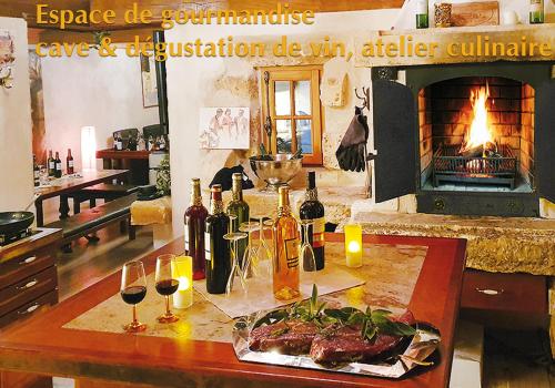 a table with bottles and glasses of wine and a fireplace at Villa 'Deux Couples' dans le Paradis des Gourmands, de paix et de quiétude - inclus Soirée Dégustation Vin & Viande in Saint-Jean-de-Côle