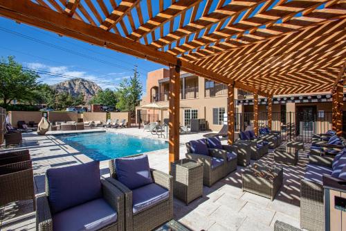 a patio with chairs and a pool with a wooden pergola at Arroyo Pinion Hotel, Ascend Hotel Collection in Sedona