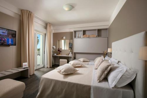 a bedroom with a large white bed with pillows at Hotel Ca' Bianca in Riccione