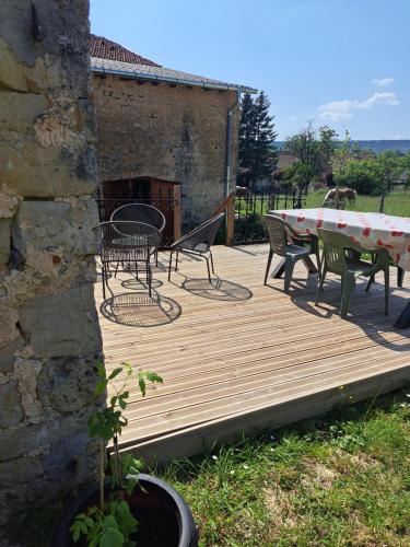 a wooden deck with a table and chairs on it at Gite une belle Histoire in Voisey