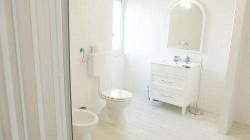 La salle de bains blanche est pourvue de toilettes et d'un lavabo. dans l'établissement Marea Case per Vacanze, à Bacoli