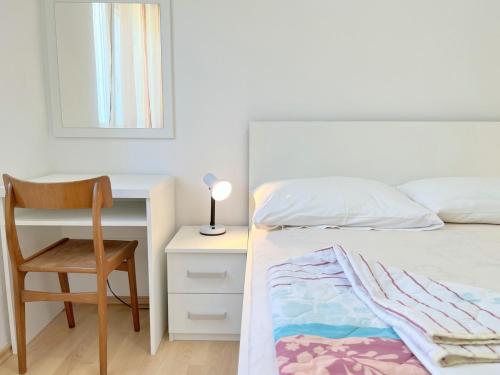 a bedroom with a bed and a desk and a chair at MiraMar Gardenn Apartmment in Rab