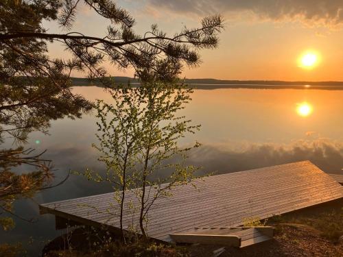 a dock on a lake with the sun setting on the water at Svanen B&B in Karlsborg