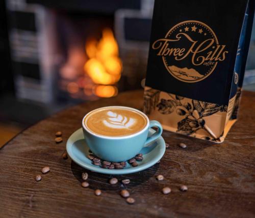 a cup of coffee on a table next to a bag of coffee beans at Cross Keys Inn Ettrickbridge in Ettrickbridge End