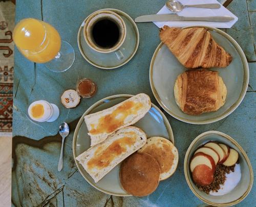 a table with two plates of breakfast foods and a cup of coffee at Hotel Habituel in Paris