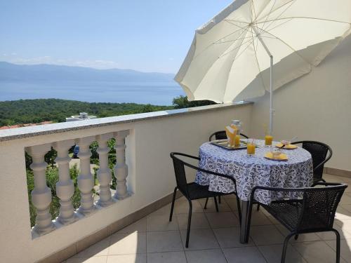 - une table avec un parasol sur le balcon dans l'établissement Apartmani Danica, à Vrbnik
