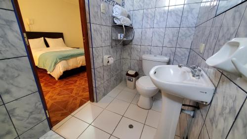 a bathroom with a sink and a toilet and a bed at Hotel Wanka Palace in Huancayo