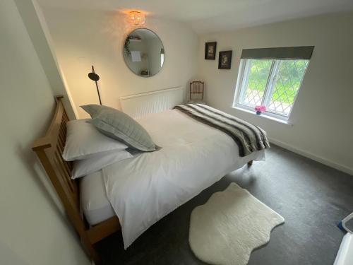 a bedroom with a white bed with pillows and a window at Highway Cottage in Kilburn