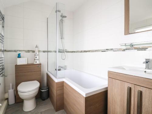a bathroom with a tub and a toilet and a sink at Sandy Shell Cottage in Conwy