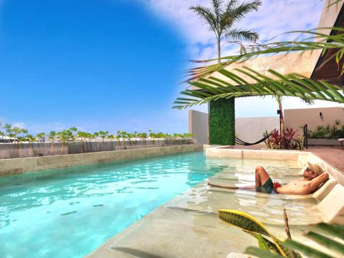 a man laying on a raft in a swimming pool at Sofía Boutique Condos by Bunik in Playa del Carmen