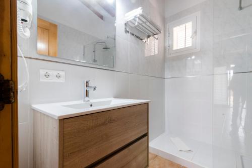 uma casa de banho branca com um lavatório e um espelho em Apartments Es Clot des Forn em Es Pujols