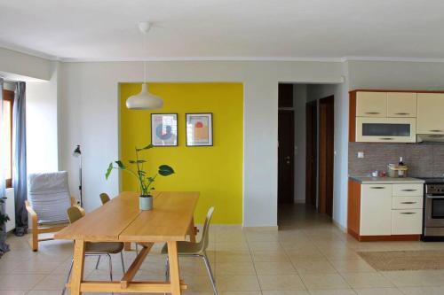uma sala de jantar com uma mesa e uma parede amarela em Thea Apartment em Tessalônica