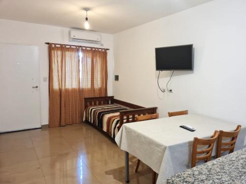 a room with two beds and a table and a television at ACHALAY, Alquileres temporarios Catamarca. DPTOS CENTRICOS HERMOSOS in San Fernando del Valle de Catamarca