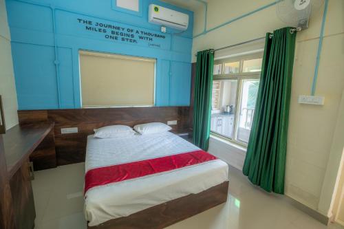 a bedroom with a bed with green curtains and a window at San Unik Homestay in Nilambūr