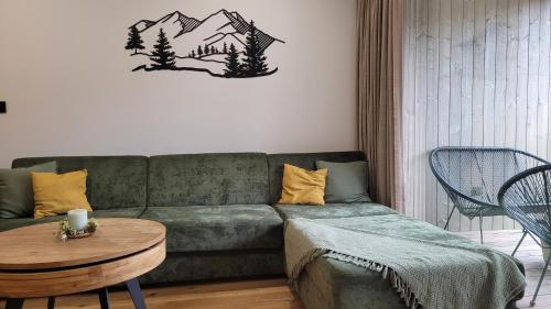 a living room with a green couch and a table at Apartmán Nicole in Tale