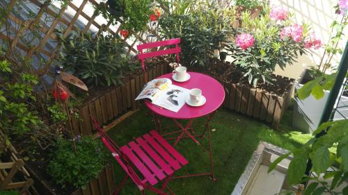 a pink table and two chairs in a garden at Hôtel de Bellevue Paris Gare du Nord in Paris