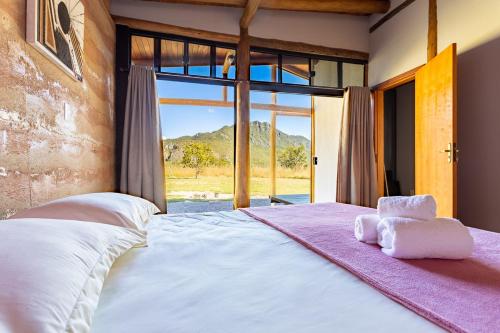 a bedroom with a large bed with a large window at Villa Taipas Chalé Iandê in Cavalcante