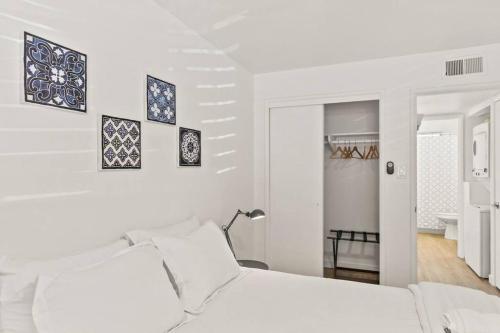 a white bedroom with a white bed and paintings on the wall at Lovely 1-bedroom condo in Biltmore - Parking in Phoenix