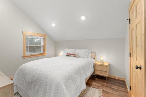ein Schlafzimmer mit einem weißen Bett und einem Fenster in der Unterkunft Little Tooth Retreat - Big Cabin in Sandpoint