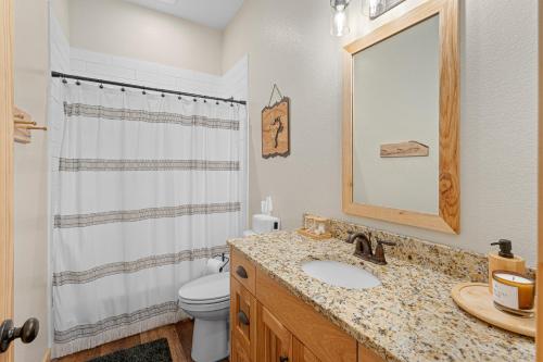 W łazience znajduje się umywalka, toaleta i lustro. w obiekcie Little Tooth Retreat - Big Cabin w mieście Sandpoint