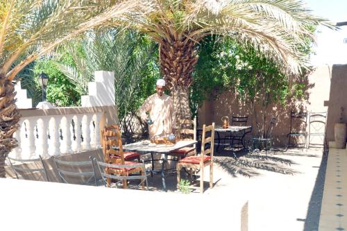 a statue of a man sitting at a table in a yard at PALM'SKOURA in Skoura