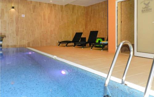a swimming pool with black chairs in a building at Stunning Apartment In Glowczyce in Główczyce