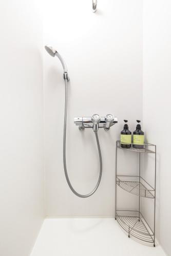 a shower in a white bathroom with a shelf at Popotel 2 KURA in Matsumoto