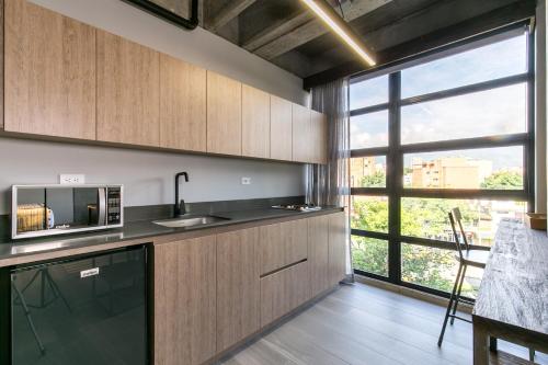 a kitchen with wooden cabinets and a large window at Factory Lofts Hotel in Medellín