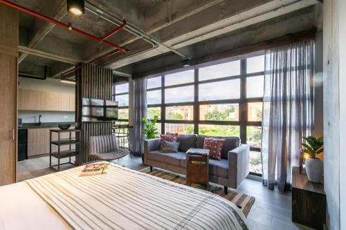a bedroom with a large bed and a living room at Factory Lofts Hotel in Medellín