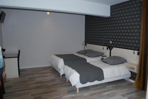 two twin beds in a room with at Hôtel Des Voyageurs in Bellevue-la-Montagne