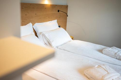 two beds in a room with white sheets and pillows at Wellness Smart Suites in Bolzano