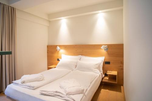 a bedroom with a bed with white sheets and pillows at Wellness Smart Suites in Bolzano