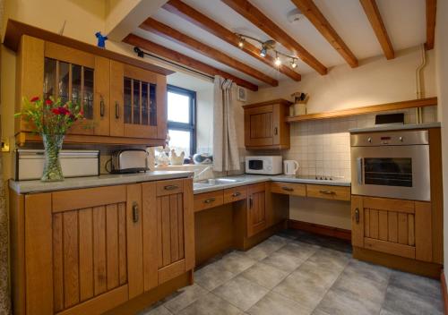 una cocina con armarios de madera y un jarrón de flores en la encimera en Carnedd Llywelyn, en Llanrwst