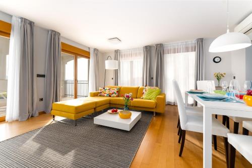 a living room with a yellow couch and a table at Großzügiges Appartement direkt am Meer mit eigenem Pool - Povile Suites in Novi Vinodolski