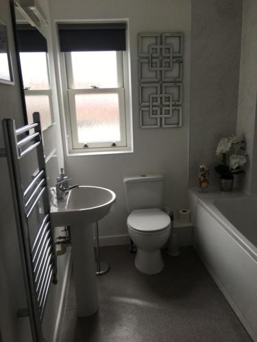 La salle de bains est pourvue de toilettes, d'un lavabo et d'une baignoire. dans l'établissement Comfortable rooms with live in host, walking distance to the High St & more, à Glastonbury