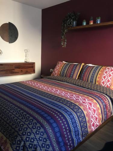 Una cama con una manta de colores encima. en Comfortable rooms with live in host, walking distance to the High St & more, en Glastonbury