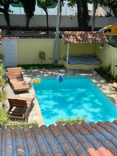 una piscina con 2 sillas y una pelota. en Pousada As Ondas, en Guarujá