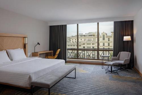 トビリシにあるコートヤード バイ マリオット トビリシのベッドと大きな窓が備わるホテルルームです。